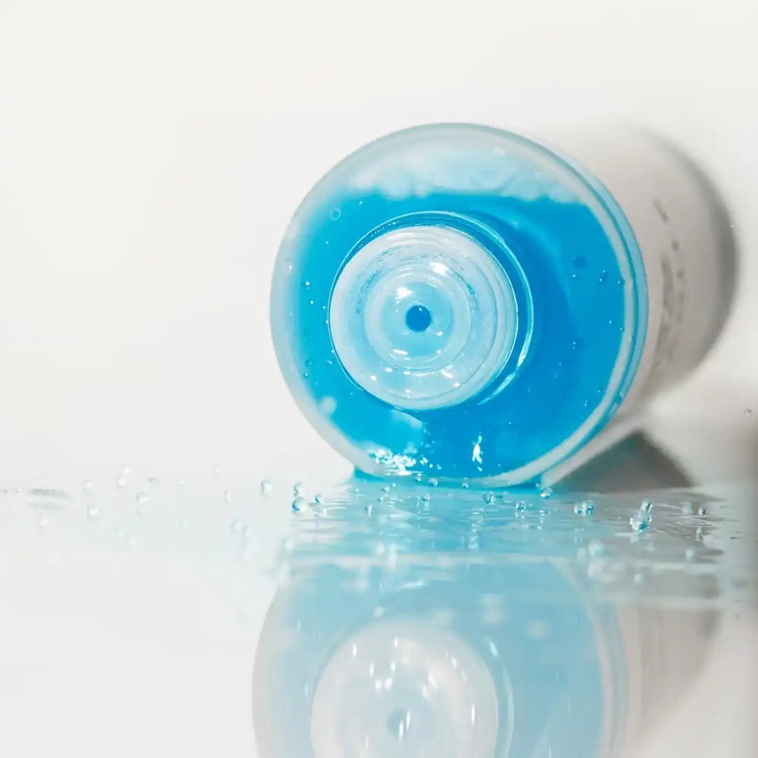 Blue liquid soap or shampoo bottle tipped on its side with product spilling out.