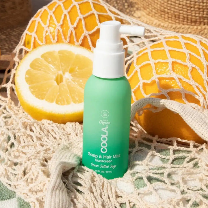 Mint green spray bottle of scalp and hair mist with citrus fruits and netting.