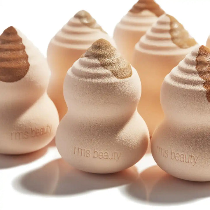 Teardrop-shaped makeup sponges with swirled tops and ’rms beauty’ branding.